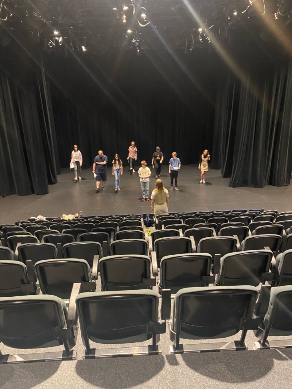 Teens on stage staring out into an empty theatre 